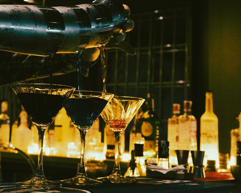 Bar de cocktails com ambiente noturno em Lisboa, iluminação quente e balcão movimentado