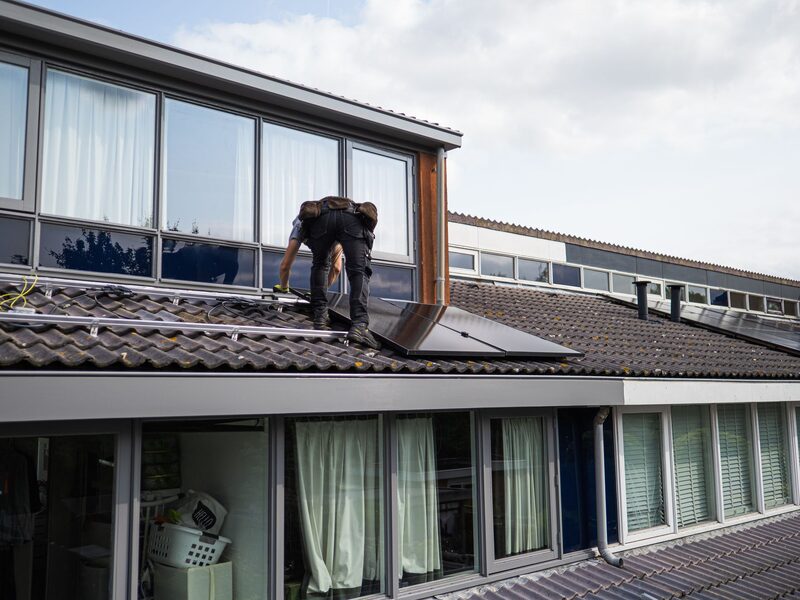 Técnico a instalar painéis solares fotovoltaicos numa cobertura em Lisboa