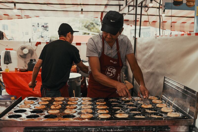Rua comercial movimentada em Arroios, Lisboa, com lojas e restaurantes de diferentes comunidades