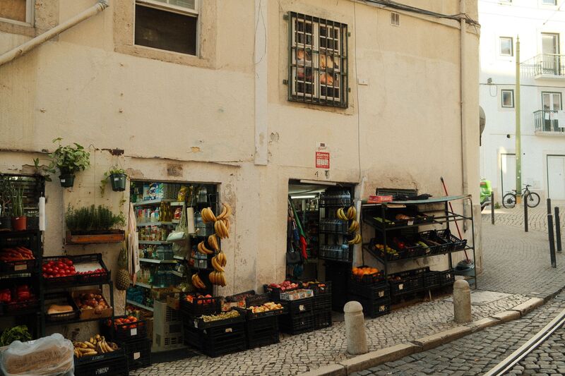 Rua residencial tranquila em Campo de Ourique, Lisboa, com prédios baixos e comércio de bairro