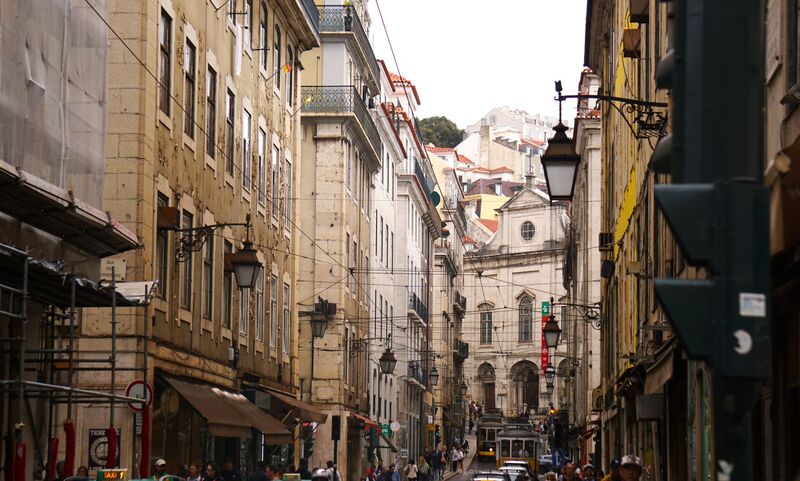 Rua comercial histórica no Chiado, Lisboa, com lojas e fachadas tradicionais